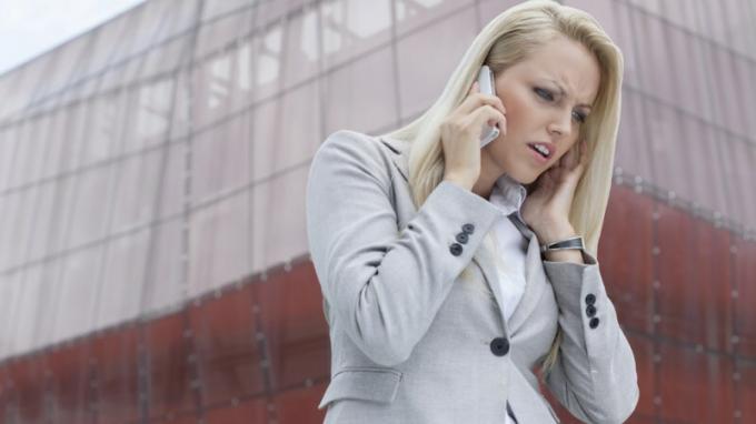 Vrouw met ADHD die aan iemand op celtelefoon luistert en boos voor de lange bouw wordt