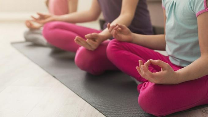 Close-up van moeder en dochtershanden die yogaoefening doen en zich thuis uitrekken. Gezondheid, sport, vrije tijd concept